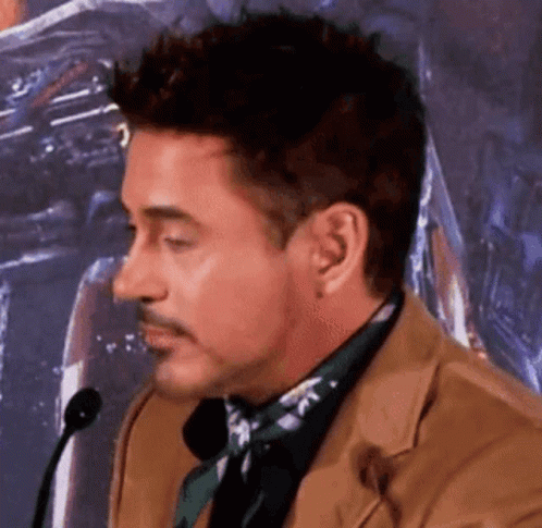Robert Downey Jr. Is Talking Into A Microphone While Wearing A Suit And Tie . GIF