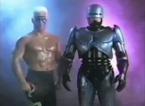 Robot Standing Next to Shirtless Man