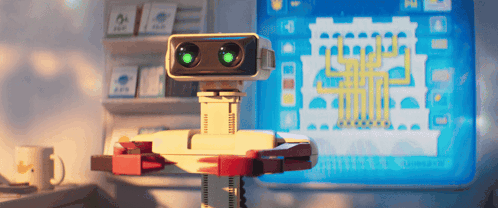 Robot With Green Eyes Sitting at Computer