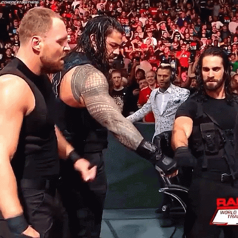 Roman Reigns And Seth Rollins Are Shaking Hands During A Wrestling Match . GIF