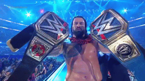 Roman Reigns Is Holding Two Wrestling Championship Belts In His Hands . GIF