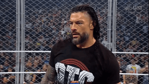 Roman Reigns Is Standing In A Wrestling Ring Wearing A T-Shirt That Says ' Tna ' . GIF