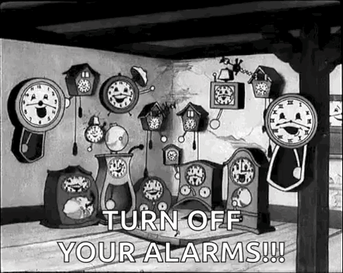 Room Filled with Clocks and Turn Off Alarms Sign