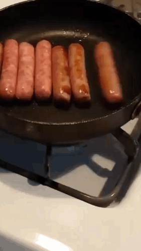 Sausages Are Cooking In A Frying Pan On A Stove Top GIF
