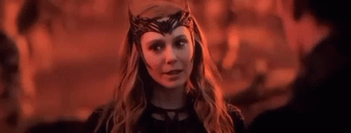 Scarlet Witch Is Wearing A Crown On Her Head And Looking At A Man In A Dark Room . GIF