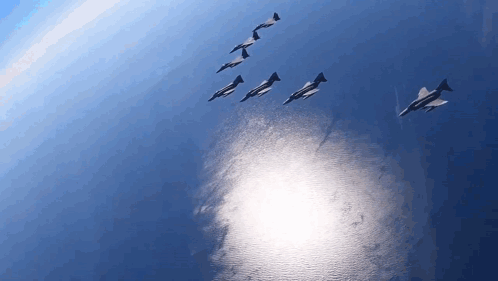several fighter jets are flying in formation over the ocean