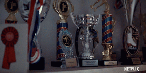 Several Trophies Are Lined Up On A Shelf And One Of Them Says First Place GIF