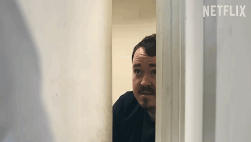 Shane Gillis Hiding Behind Door GIF