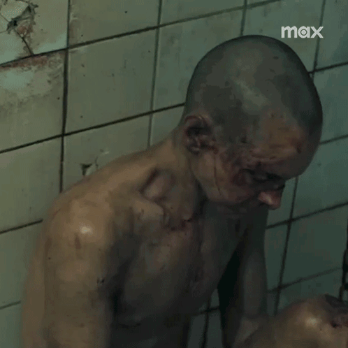 Shaved Head Man Standing Before Tiled Wall Saying Max