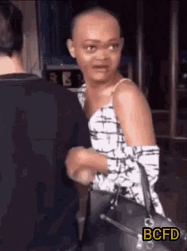 Shaved Head Woman Holding Purse Talking