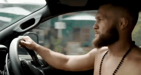 Shirtless Bearded Man Driving Car