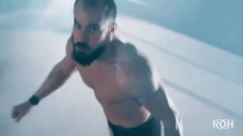 Shirtless Bearded Man Jumping in Dark Room