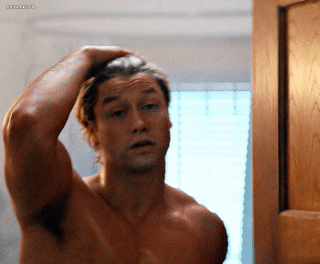 Shirtless Man Adjusting Hair in Mirror With Ocean