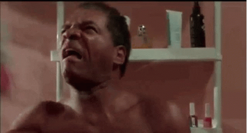 Shirtless Man Crying In Bathroom Next To Perfume Shelf GIF