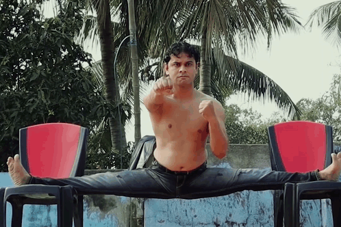 Shirtless Man Doing Split on Chair