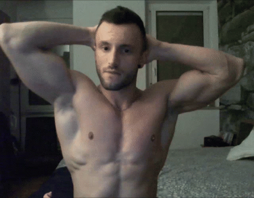 Shirtless Man Flexing Muscles in Bedroom