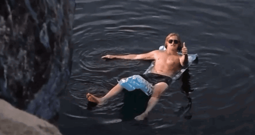 Shirtless Man Floating on Raft Giving Thumbs Up