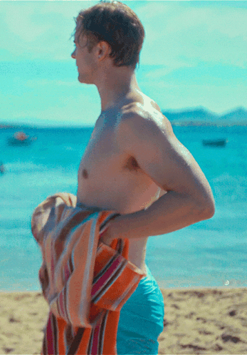 Shirtless Man Holding Towel Over Shoulder on Beach