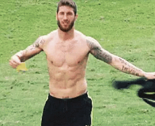 Shirtless Man Holding Yellow Card on Soccer Field