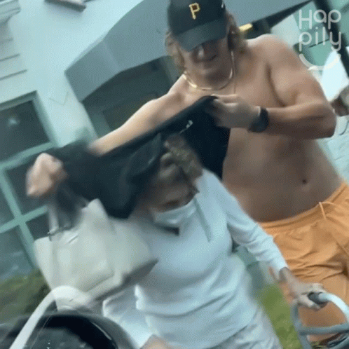 Shirtless Man in Black Hat P Helping Elderly Woman