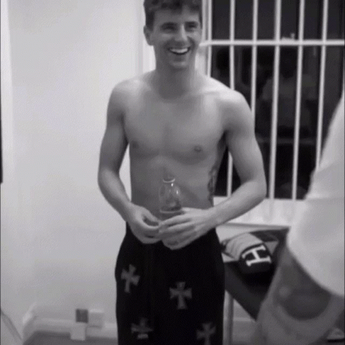 Shirtless Man in Black Shorts With Crosses Smiling