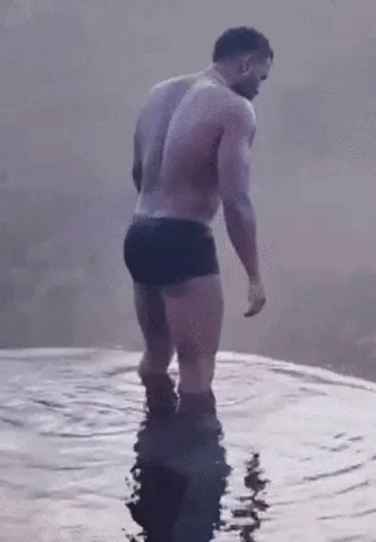 Shirtless Man In Black Trunks Standing In Water GIF