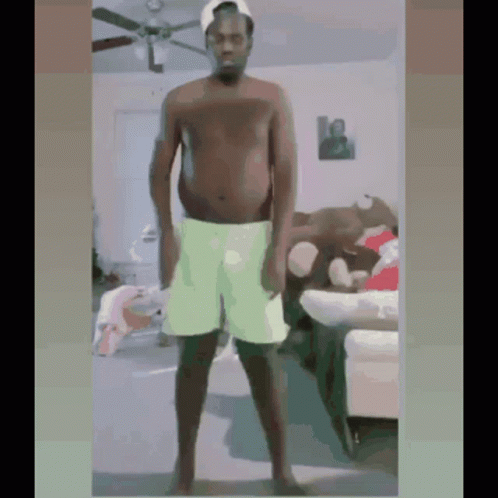 Shirtless Man In Green Shorts Standing In Living Room GIF