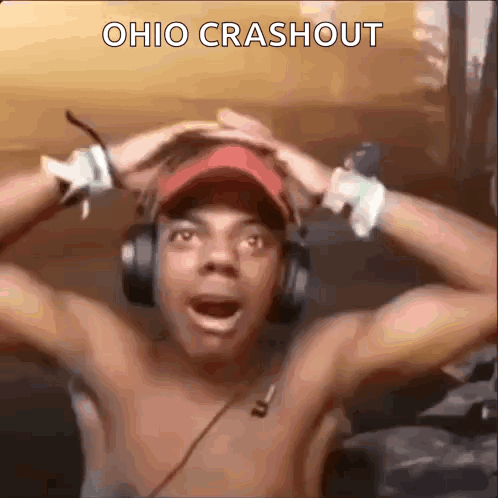 Shirtless Man in Headphones and Red Hat Holding Head