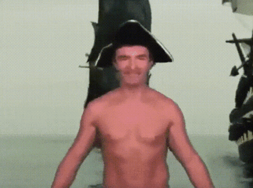 Shirtless Man in Pirate Hat in Front of Statue
