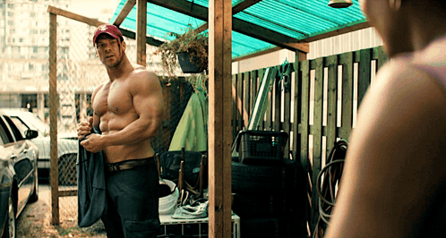 Shirtless Man in Red Hat Standing in Front of Woman