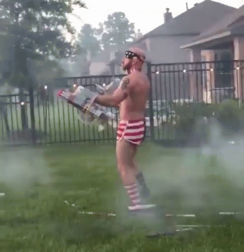 Shirtless Man in Red White and Blue Shorts Holding Flamethrower