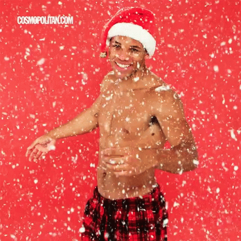 Shirtless Man in Santa Hat Standing in Snow