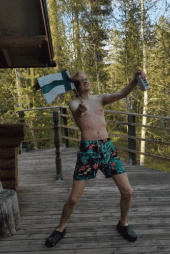 Shirtless Man in Trunks Holding Flag and Beer T