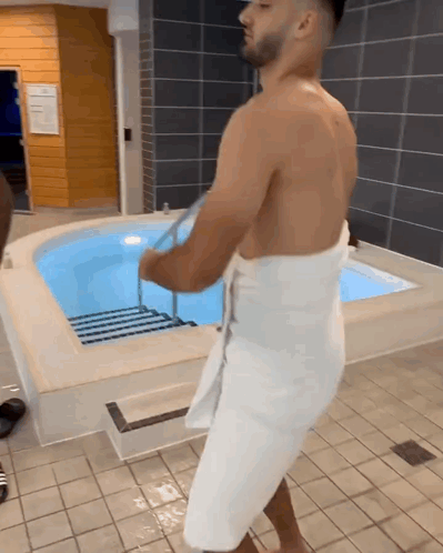 Shirtless Man in White Towel by Pool