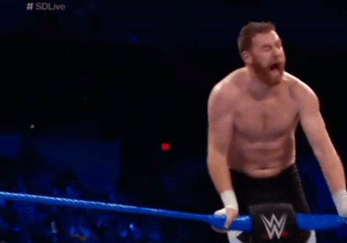 Shirtless Man Kneeling in Wrestling Ring With W Logo