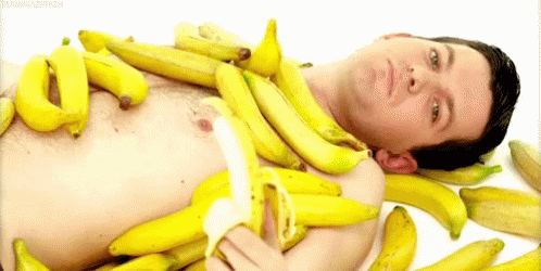 Shirtless Man Lying on Pile of Bananas