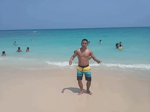 Shirtless Man On Beach Giving Peace Sign GIF