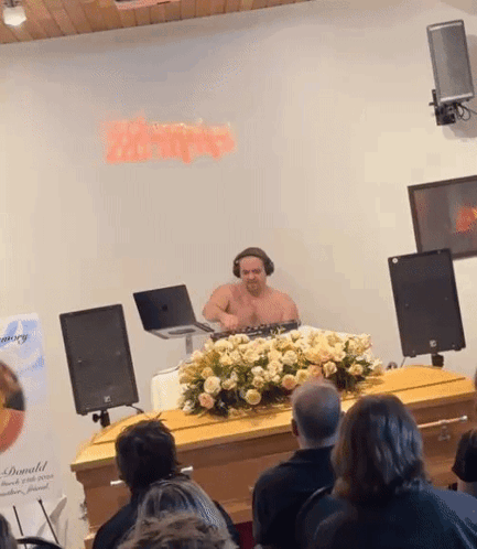 Shirtless Man Playing Music In Front Of Donald Sign GIF
