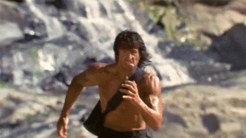 Shirtless Man Running in Front of Waterfall