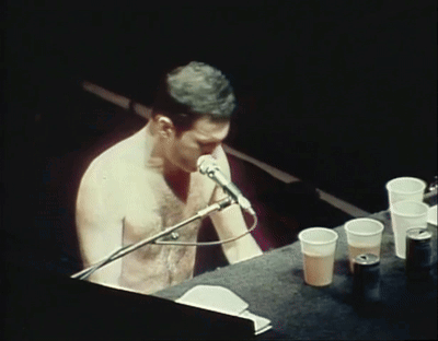 Shirtless Man Singing Into Microphone