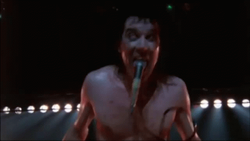 Shirtless Man Singing Into Microphone