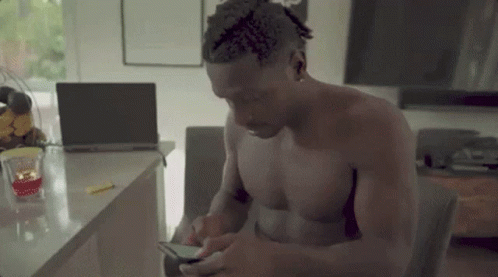 Shirtless Man Sitting at Laptop on Phone