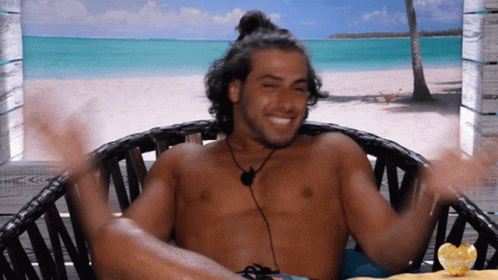 Shirtless Man Sitting on Beach With Arms Outstretched