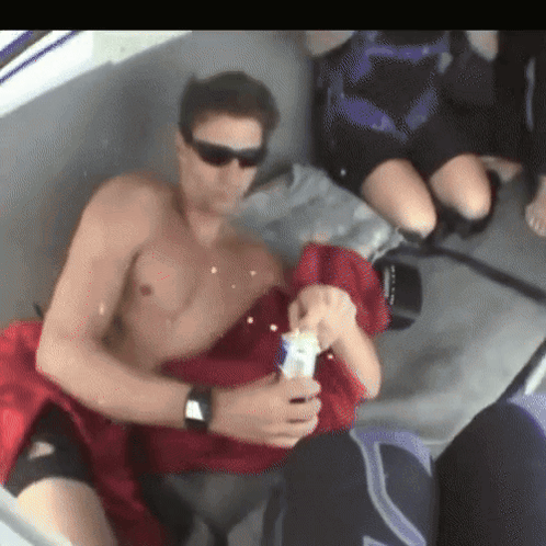 Shirtless Man Sitting on Boat Holding Bottle