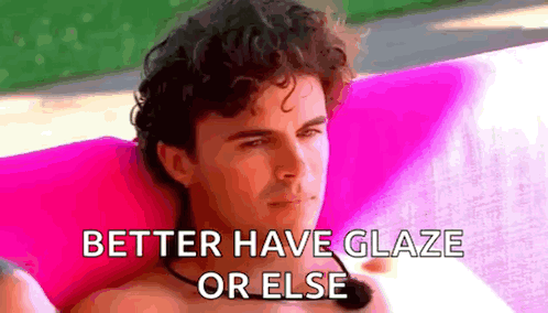 Shirtless Man Sitting on Pink Couch with Microphone and Pink Pillow