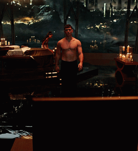 Shirtless Man Standing by Candlelit Window