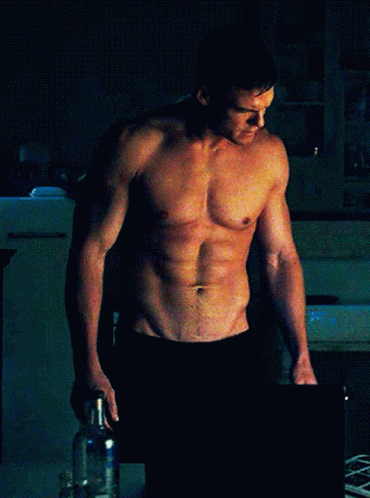 Shirtless Man Standing Hands On Hips In Dark Room GIF