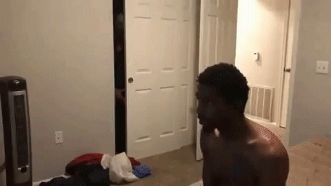 Shirtless Man Standing In Bedroom Next To Fan And Closet GIF
