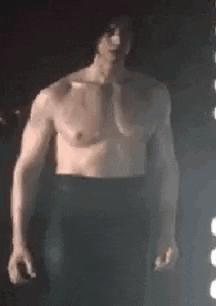Shirtless Man Standing In Dark In Front Of Light GIF