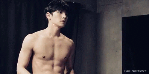Shirtless Man Standing in Front of Black Curtain